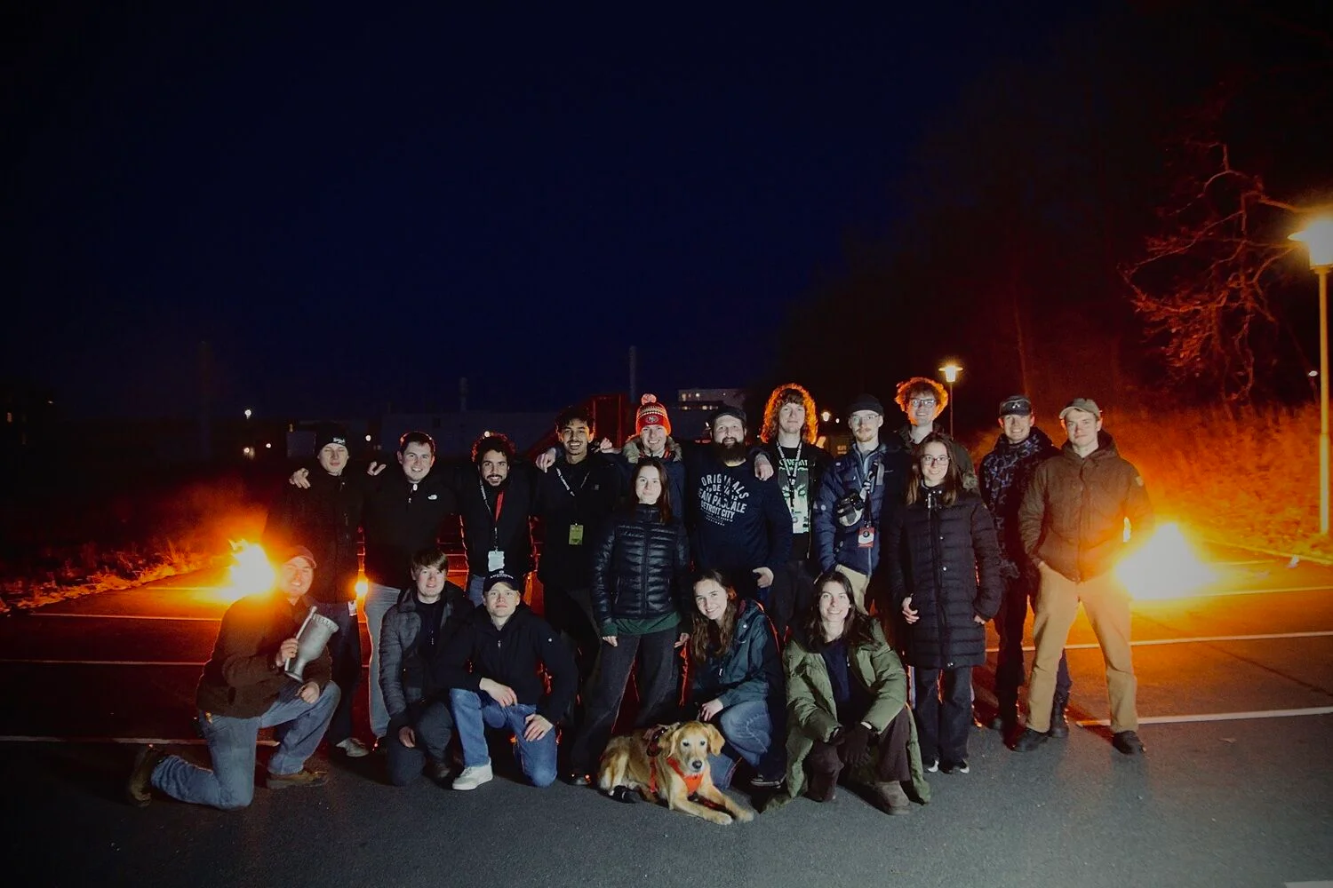 The DanSTAR Rocketry team gathered outdoors at night, with all group members and the dog in view.