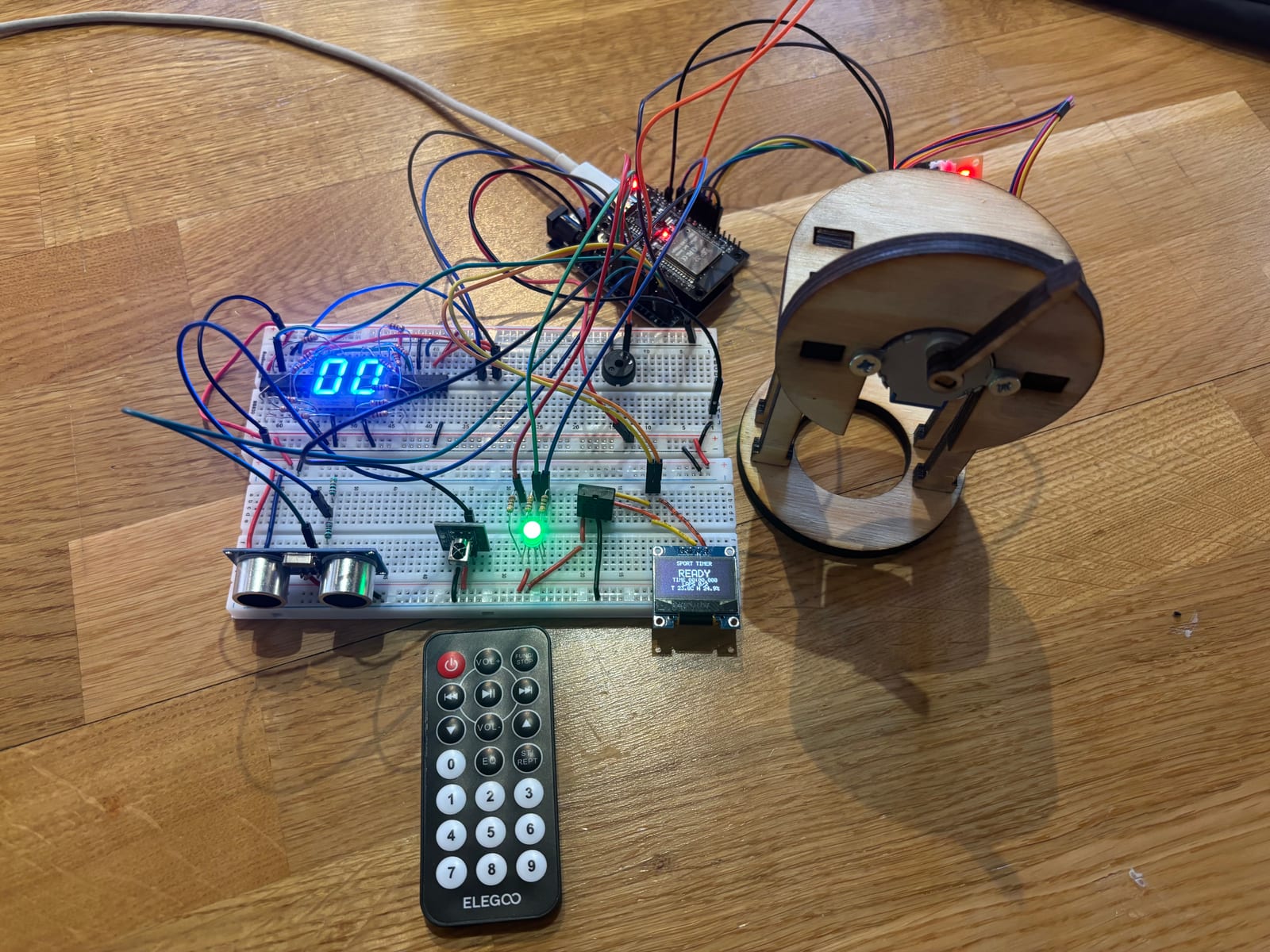 ESP32 timing prototype on a breadboard, with ultrasonic sensor, displays, wiring, and a stepper-driven dial.